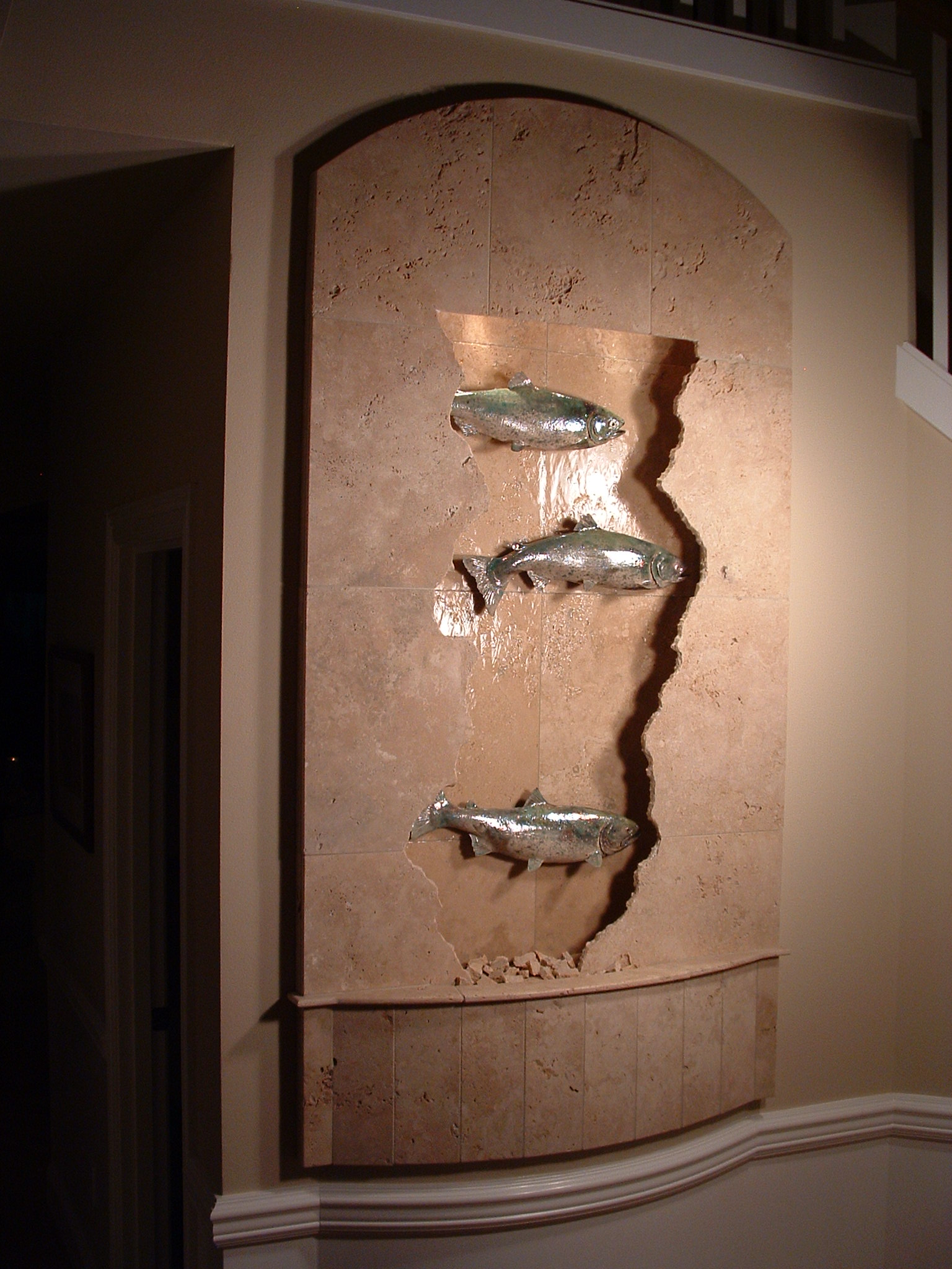Issaquah, WA. residence, existing home. 43 in x 7 ft fractured travertine salmon wall curved basin front makes use of existing wall curve, waterwall size makes use of existing art nook, lighting in valance, crushed travertine bits top out basin, remote basin.