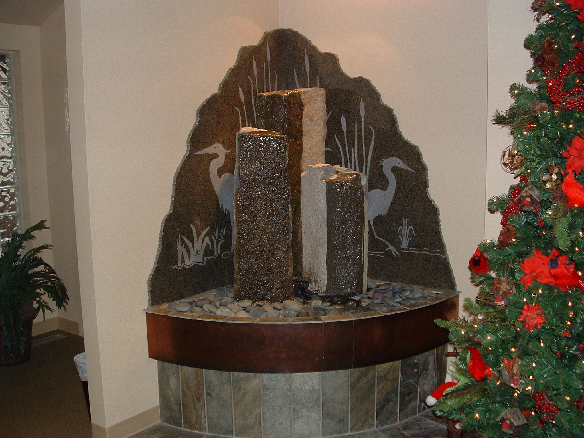 North Seattle, WA. Dr. Lee dental, existing building. 6 ft x 7ft tall, backdrop is green granite with sandblasted images, three basalt columns, copper front basin, quartz base, topped out with beach rock, over head lighting, auto fill easy drain.