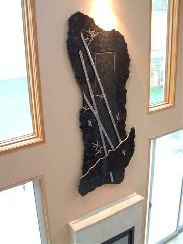 This piece is 4' by 10' tall, made of granite and is mounted on the wall above the fire place 9' off the floor. There is hand made stainless steel bamboo and dragon fly's mounted out in front of the water that is running down the center section wave wall and lighting illuminating from above.